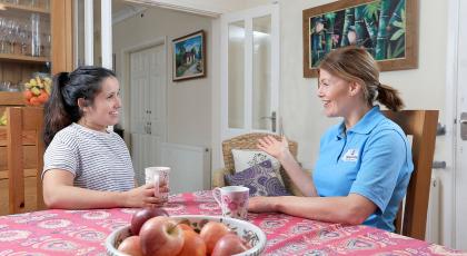 A young woman having tea and a chat with her physio