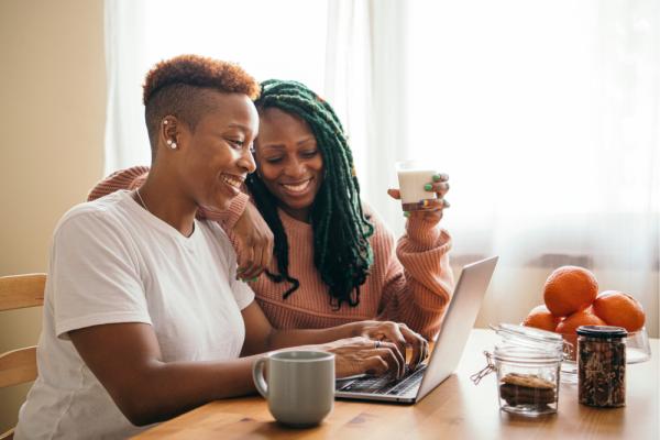 Lesbian couple having breakfast working on laptop